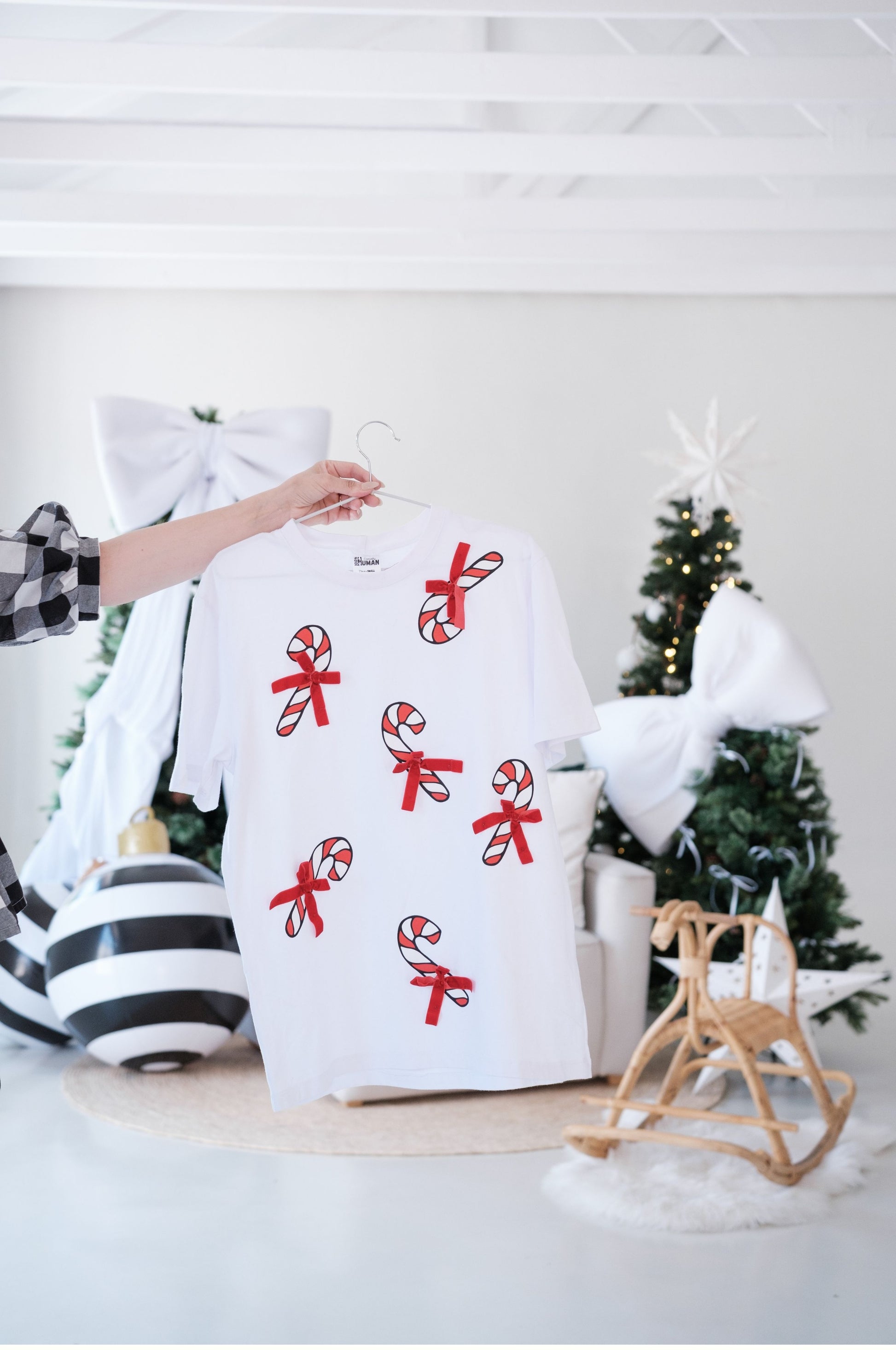 White Christmas t-shirt with multiple candy cane prints and red bows hanging festive clothing South Africa
