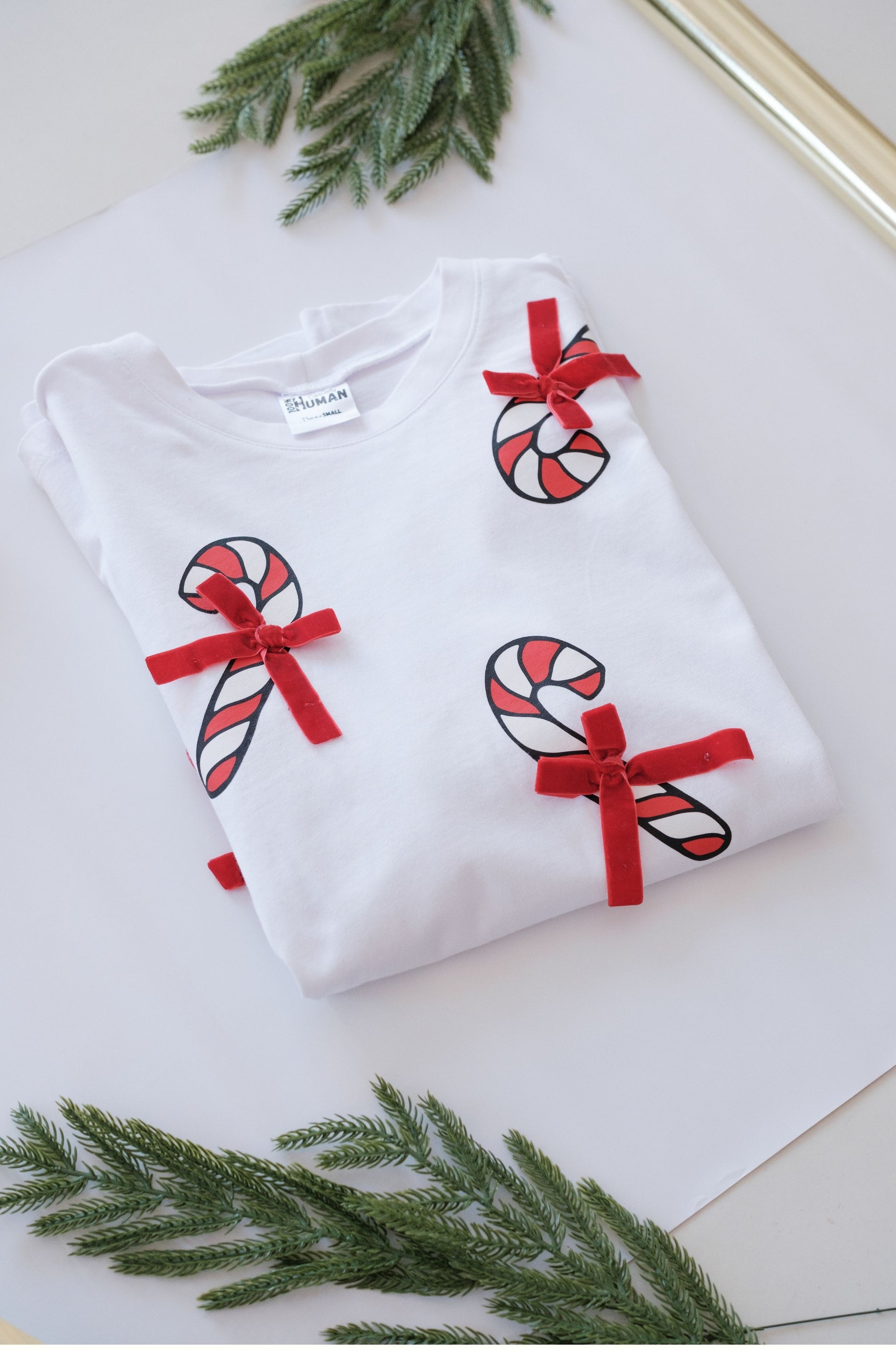 Detailed flat lay of white Christmas shirt with candy cane and red bow design festive aesthetic South Africa