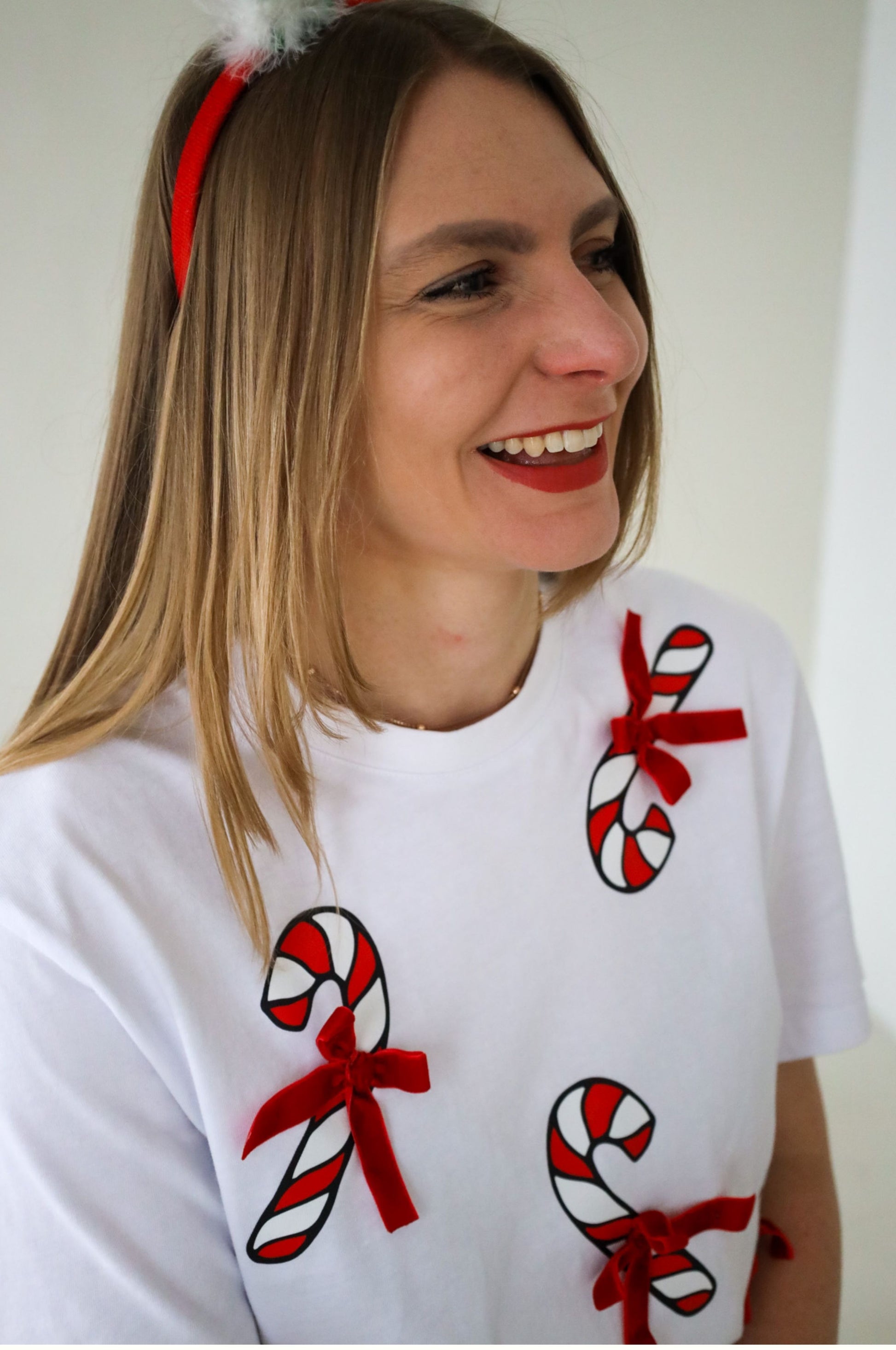Woman wearing white Christmas t-shirt with candy cane and red bow design festive outfit South Africa