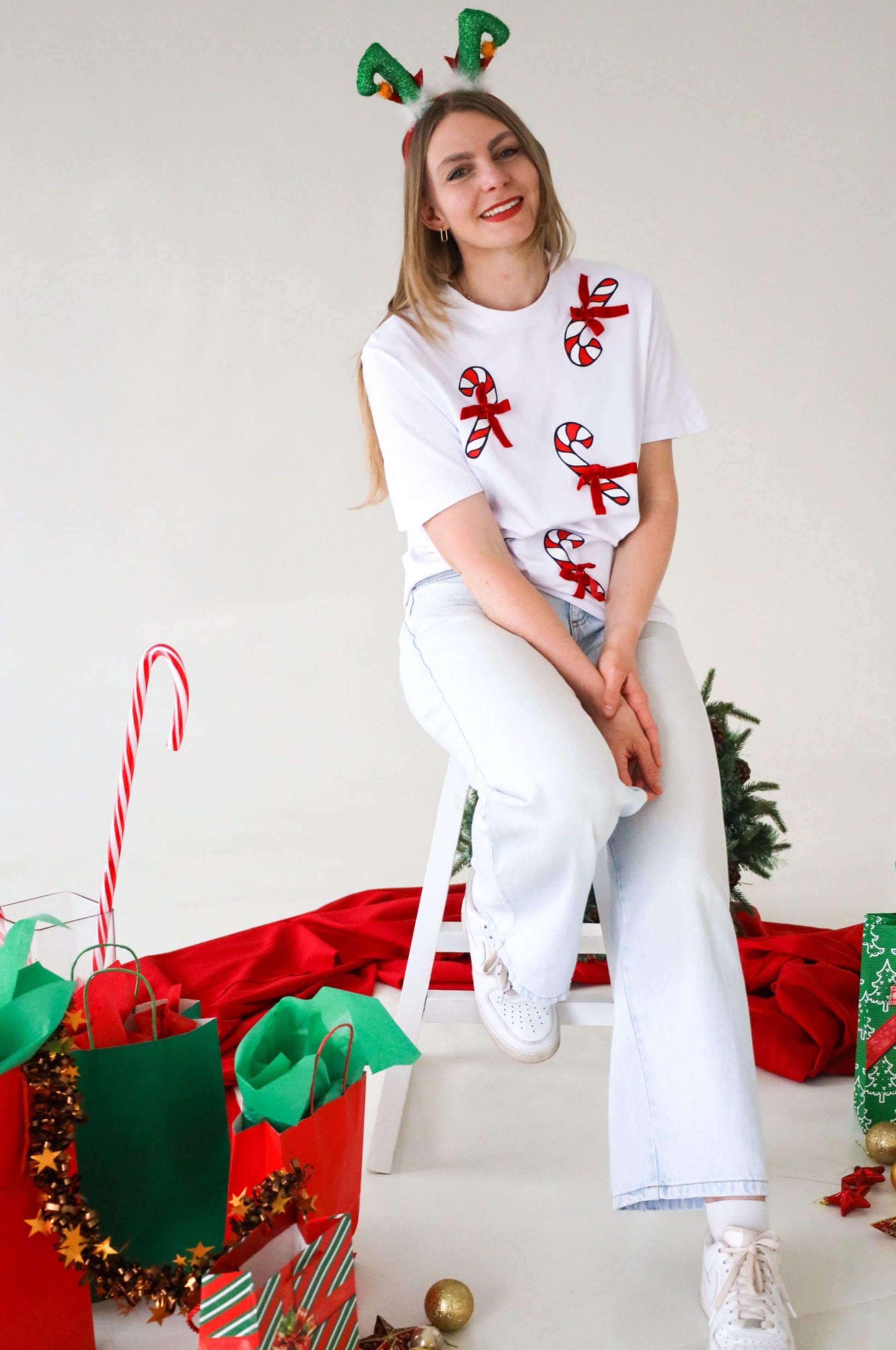 Woman sitting wearing cute Christmas candy cane t-shirt with festive decorations and gifts South Africa