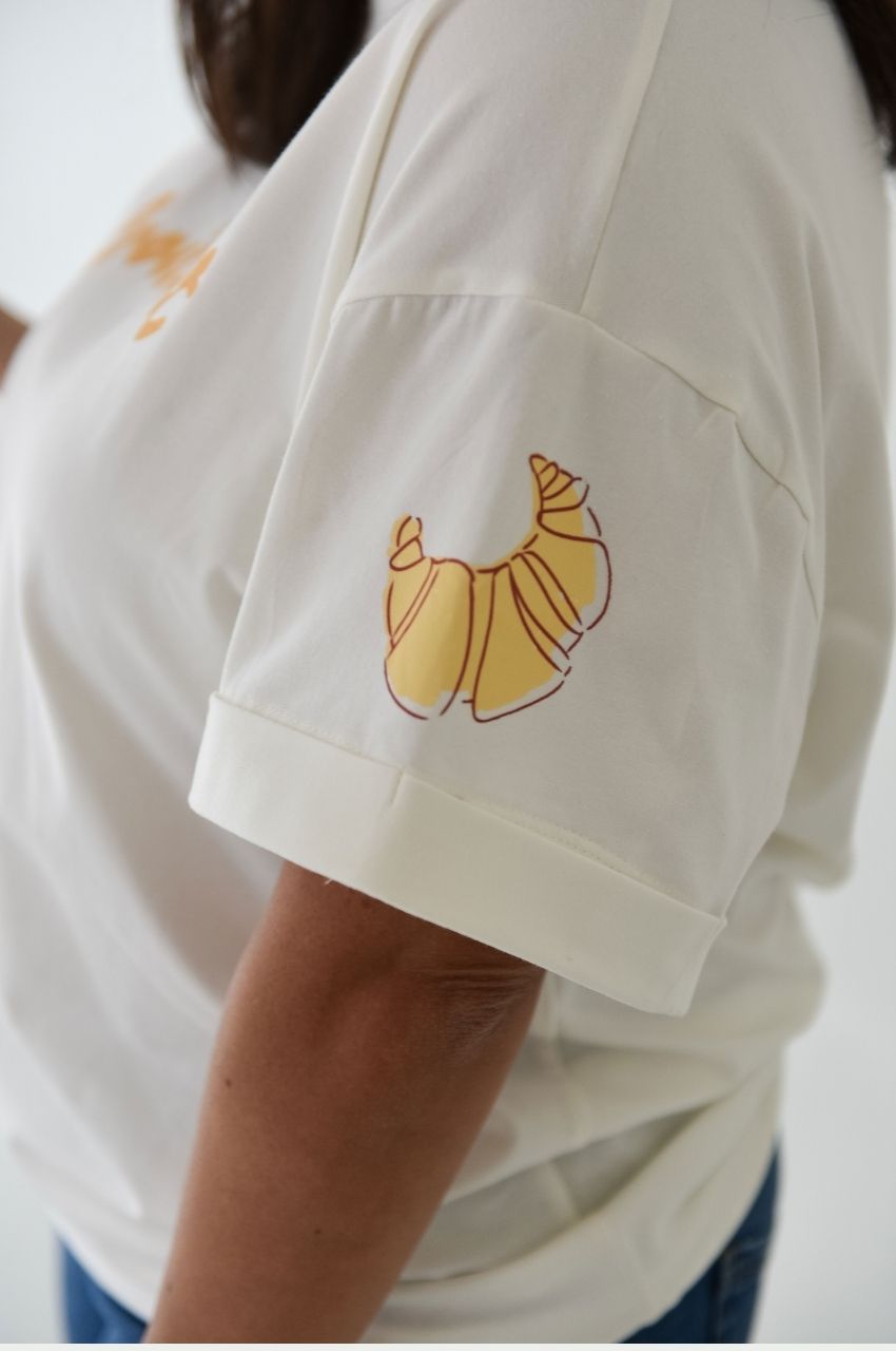 Close up of croissant illustration on sleeve white t-shirt minimalist design South Africa