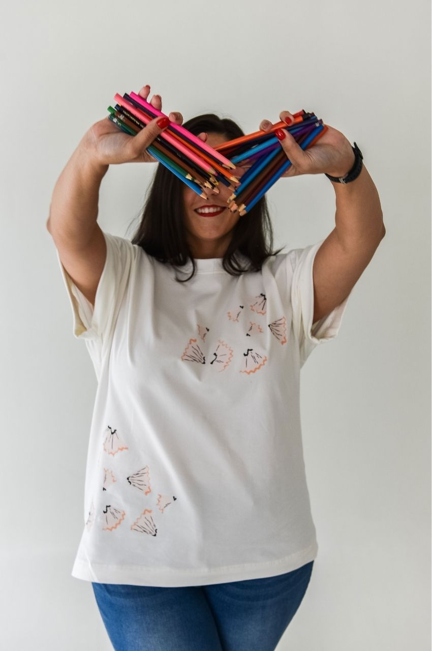 Woman holding colored pencils wearing white t-shirt with creative pencil shaving print design South Africa