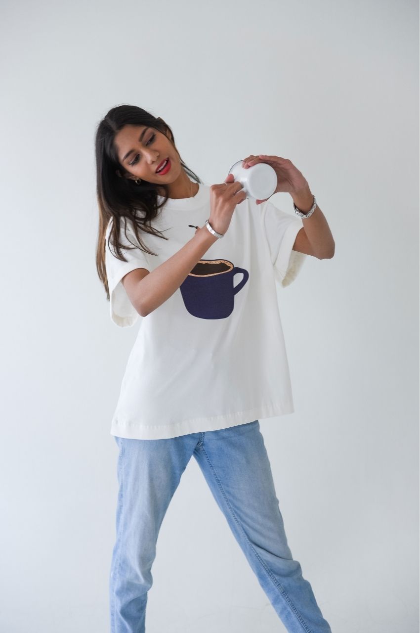 Playful woman holding cup wearing t-shirt with lady diving into coffee illustration lifestyle fashion