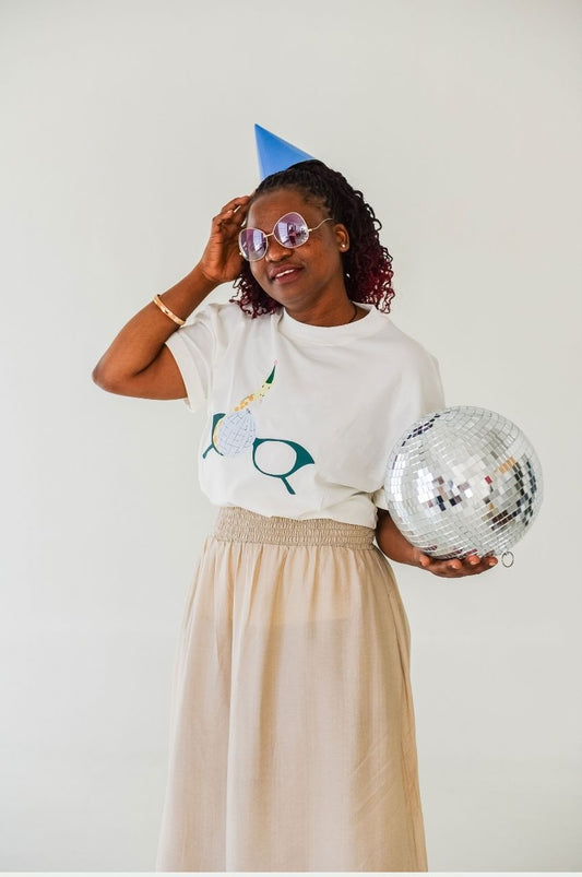 Woman wearing white t-shirt with giraffe disco ball party graphic holding mirror ball South Africa