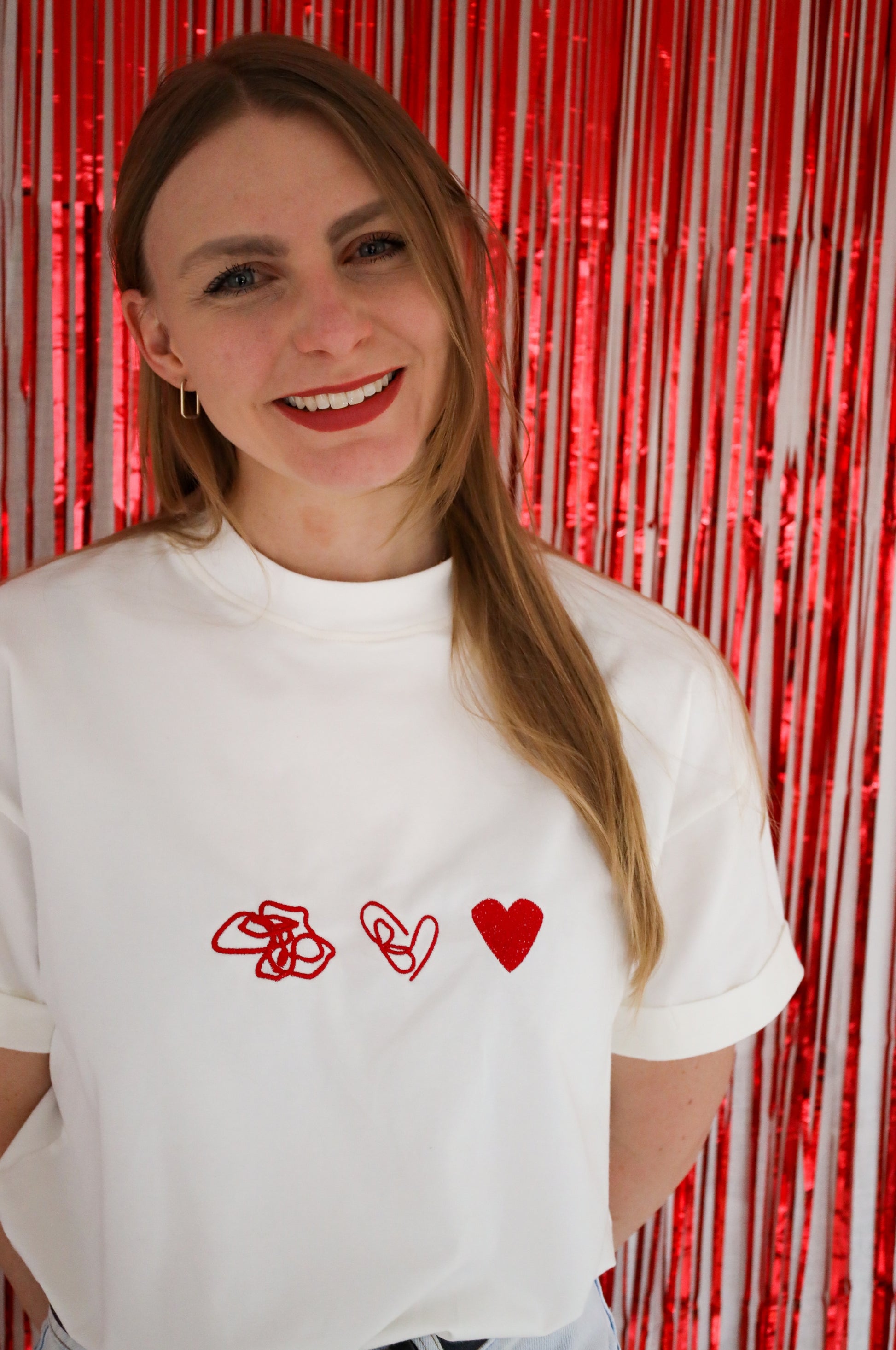 Close-up of woman wearing white cotton t-shirt with red heart embroidery, quirky graphic tee South Africa