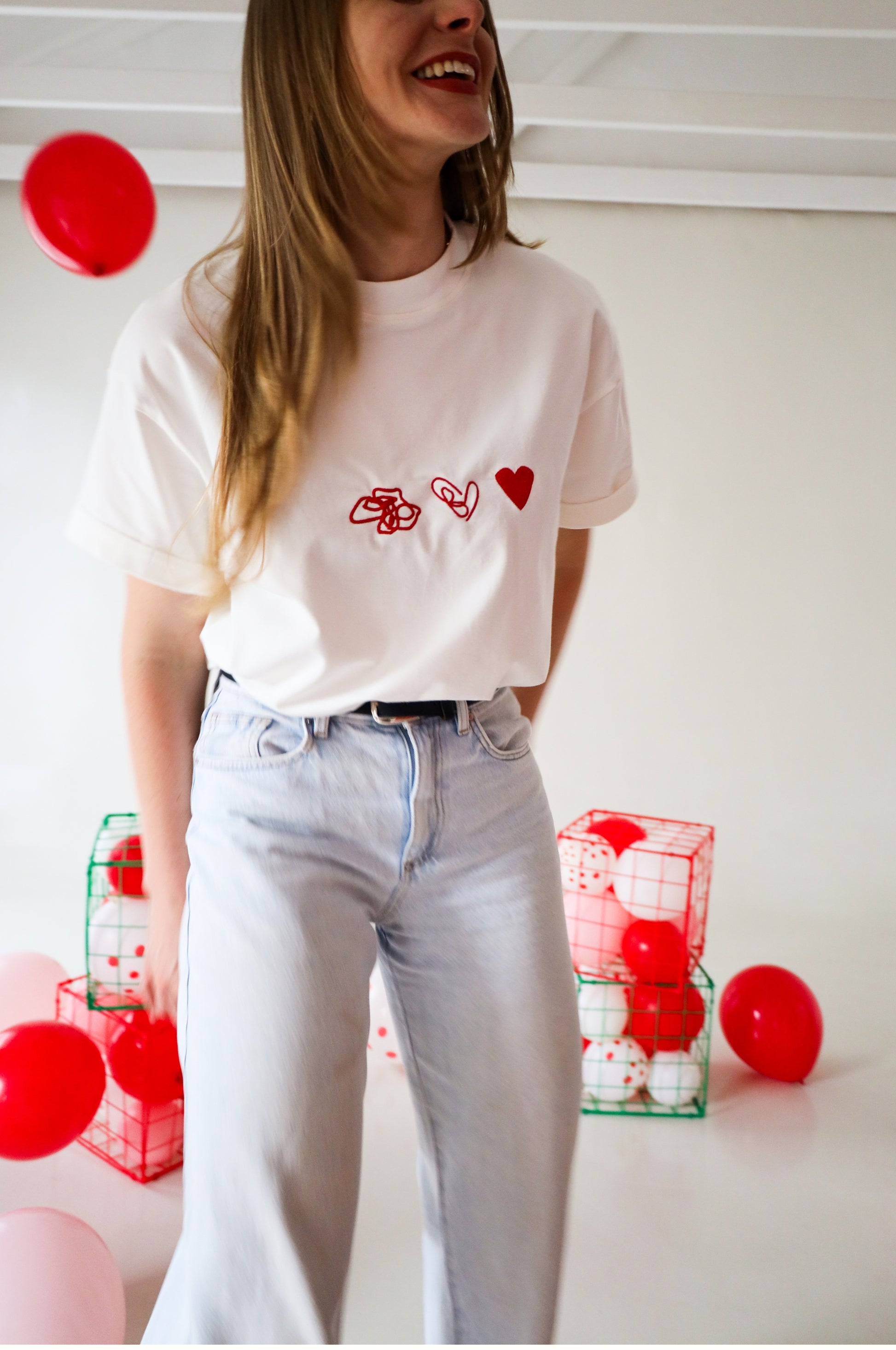 Woman wearing white graphic t-shirt with red heart embroidery, 100% cotton quirky tee in lifestyle setting South Africa