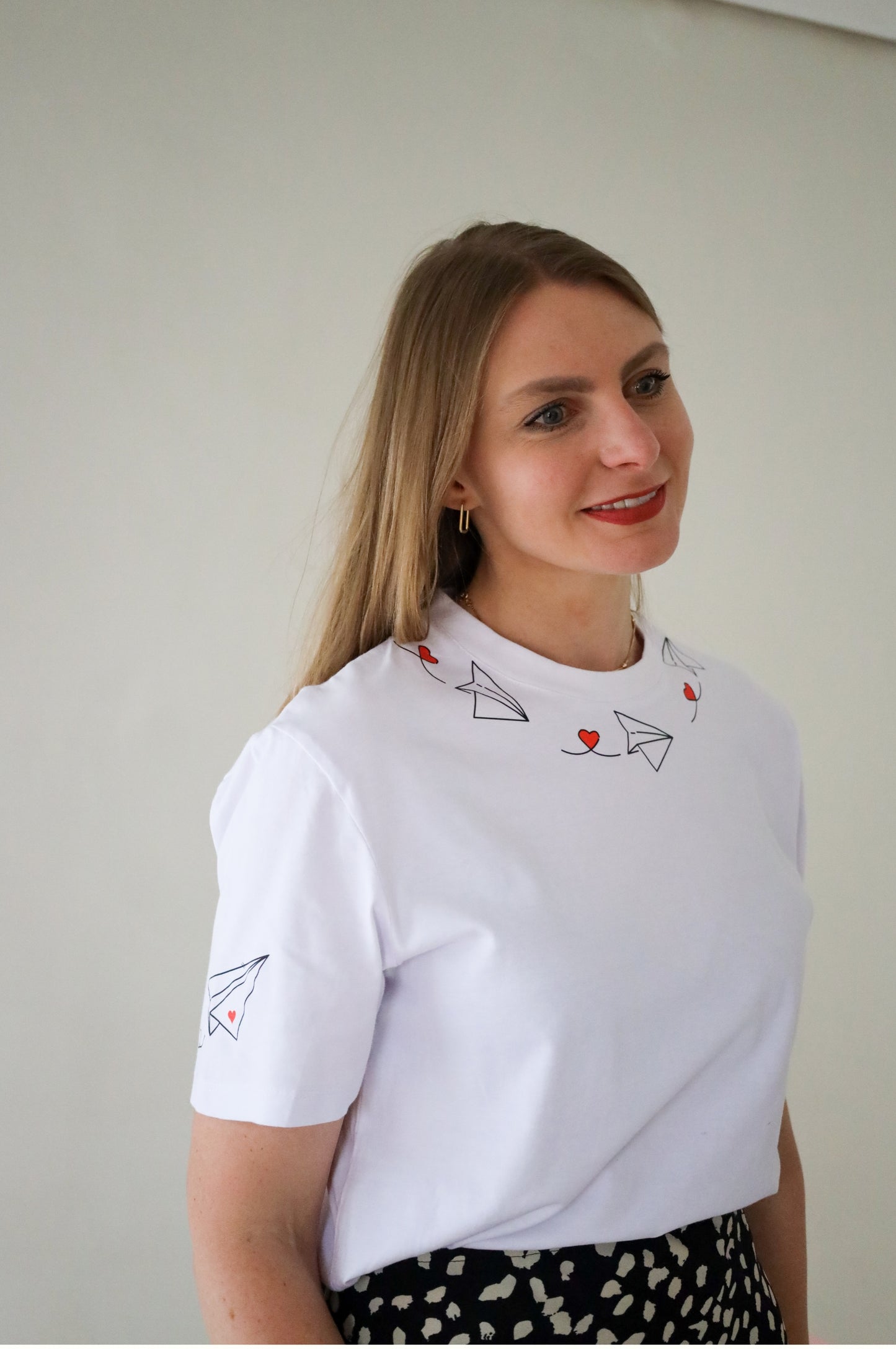 Woman wearing white graphic t-shirt with paper plane heart design, 100% cotton quirky tee South Africa