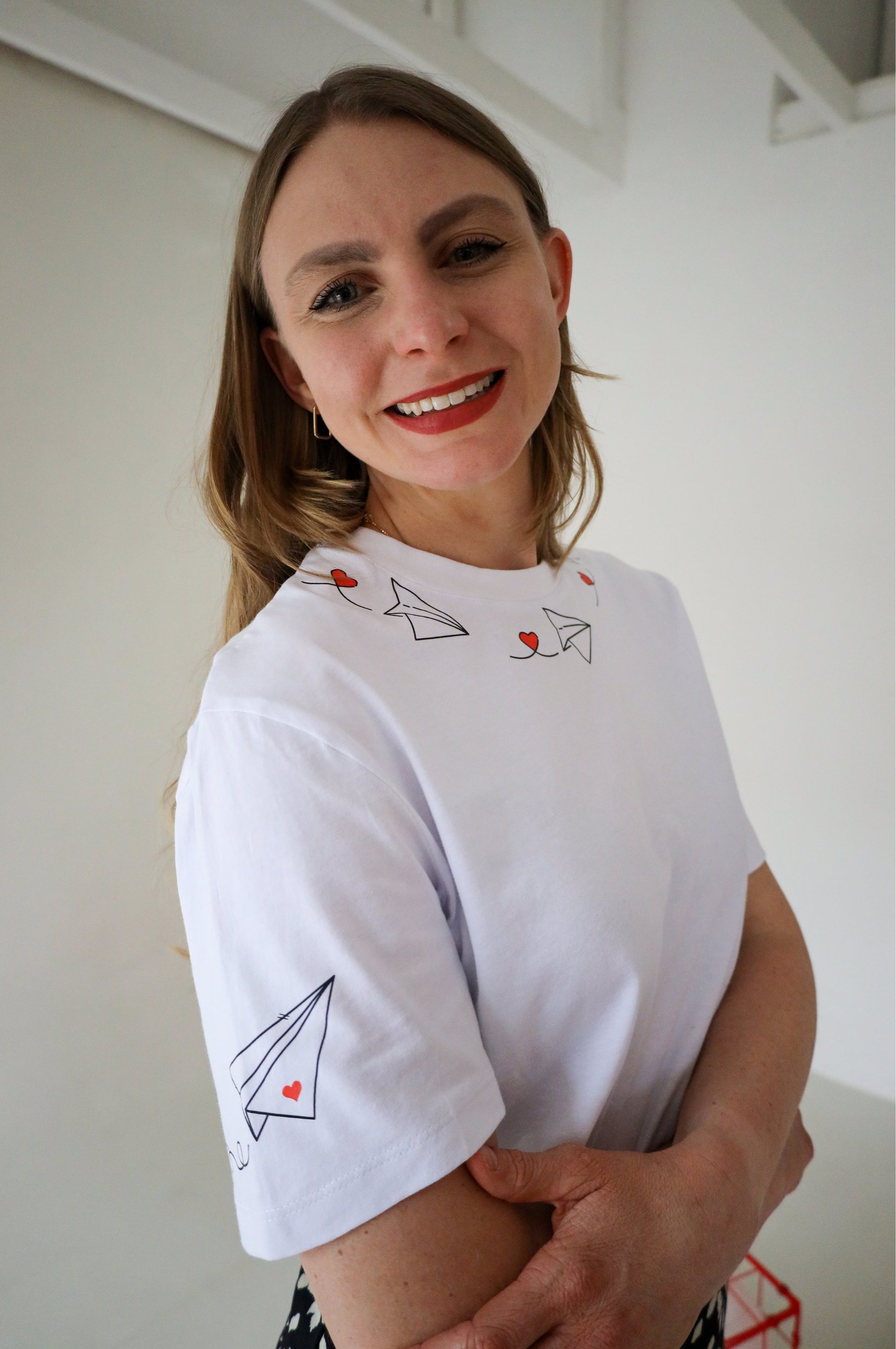 Woman wearing white graphic t-shirt with heart and paper plane design, 100% cotton quirky tee South Africa