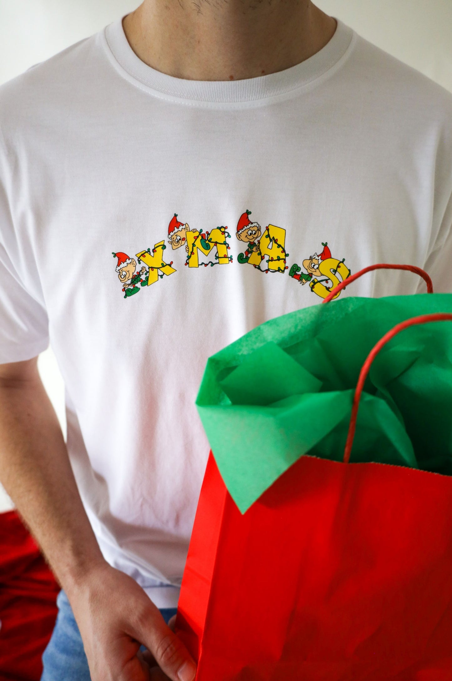 Close-up of white Christmas t-shirt with colourful XMAS elf design holding gift bag festive clothing South Africa