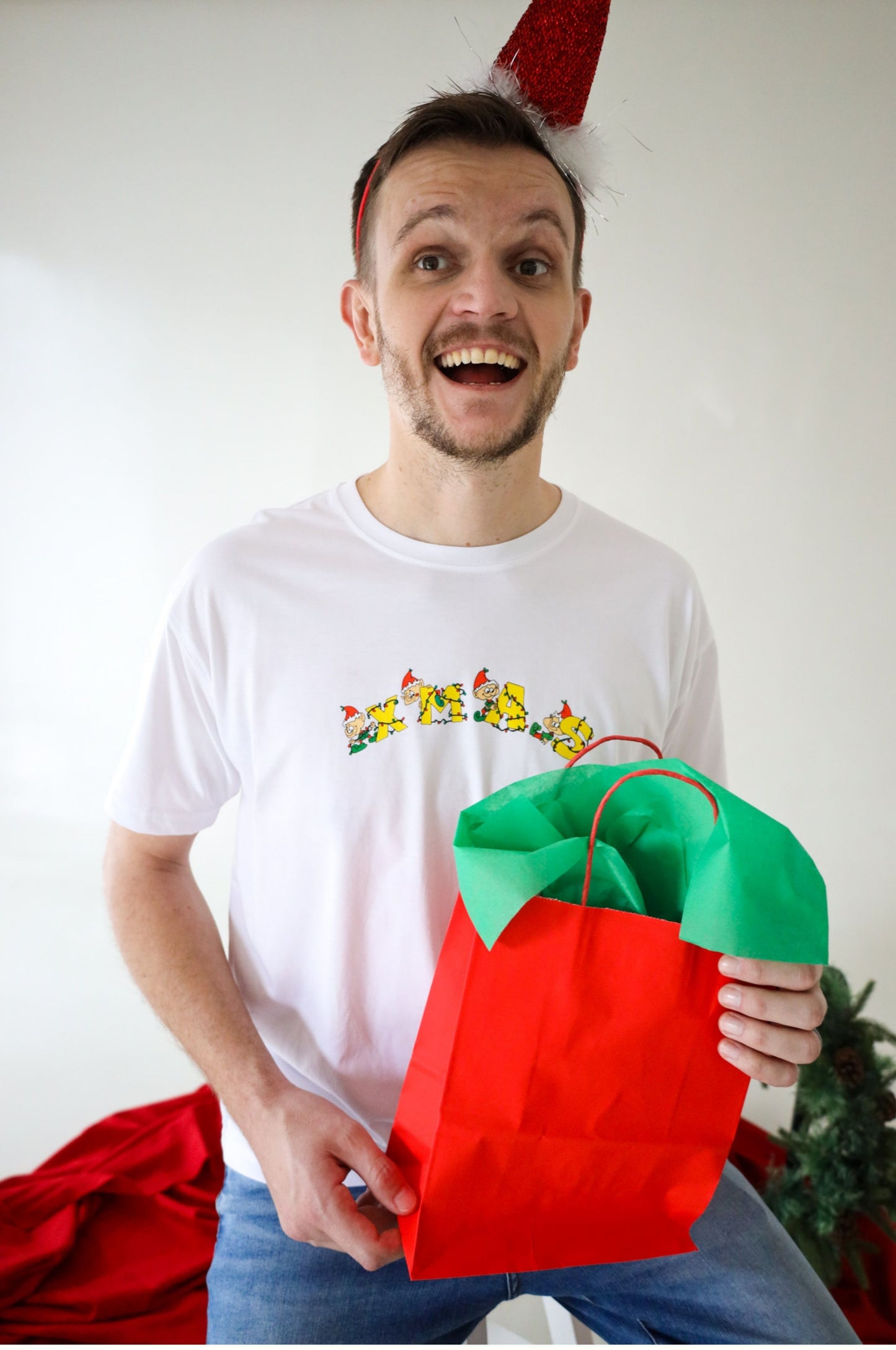 Man wearing funny XMAS Christmas t-shirt with elf design holding a red gift bag festive outfit South Africa